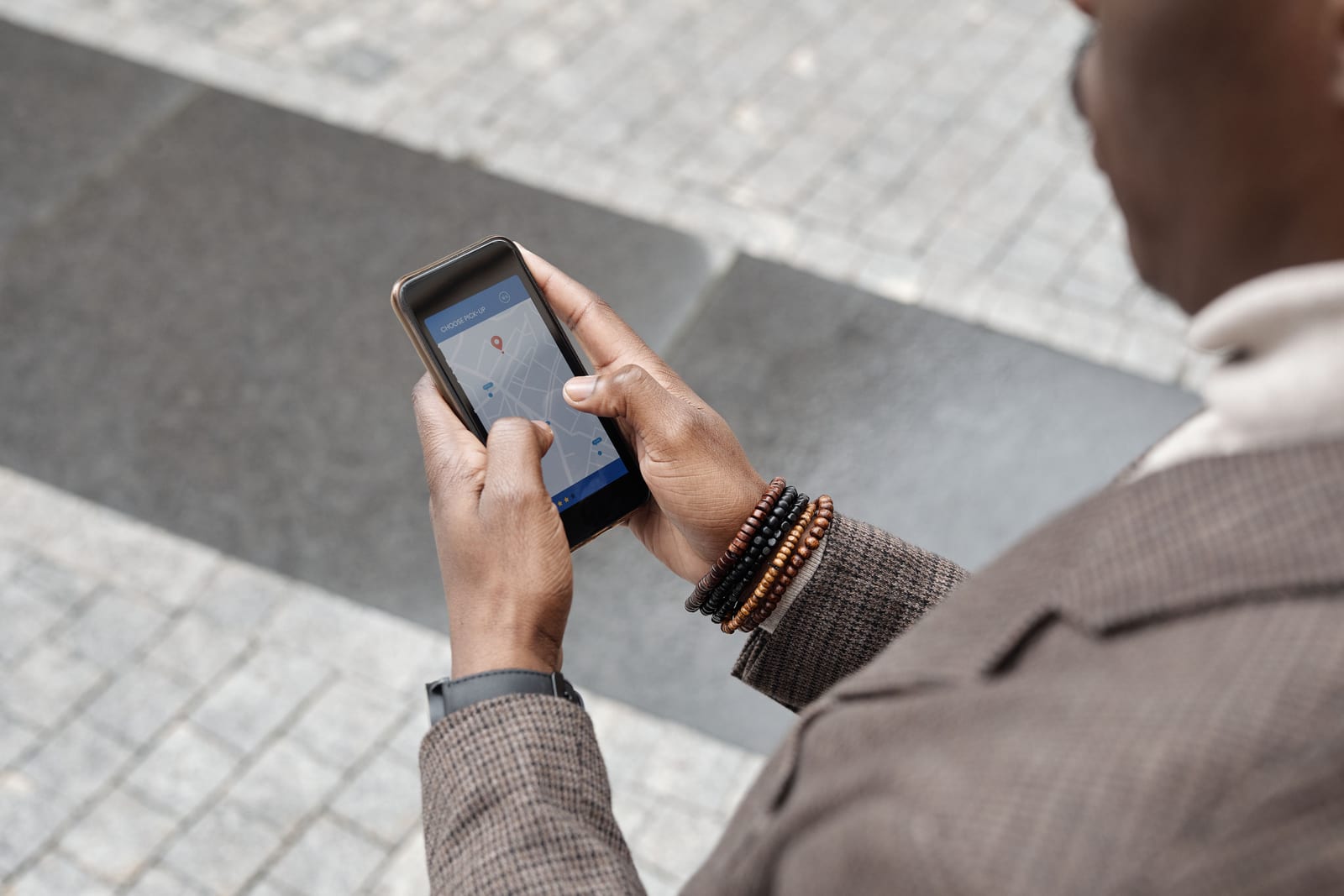 Person holding a phone showing a map on a cobblestone Old Town street